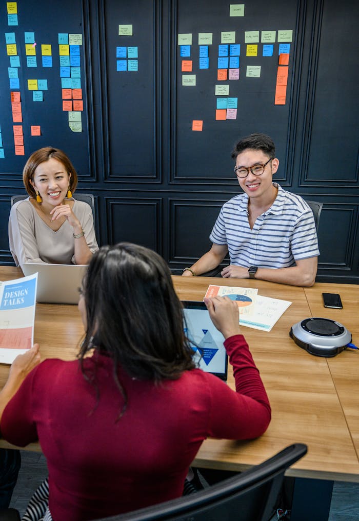 Group of colleagues engaged in a productive office meeting with laptops and sticky notes.